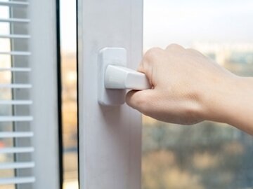 Hand am Fenstergriff zum Lüften